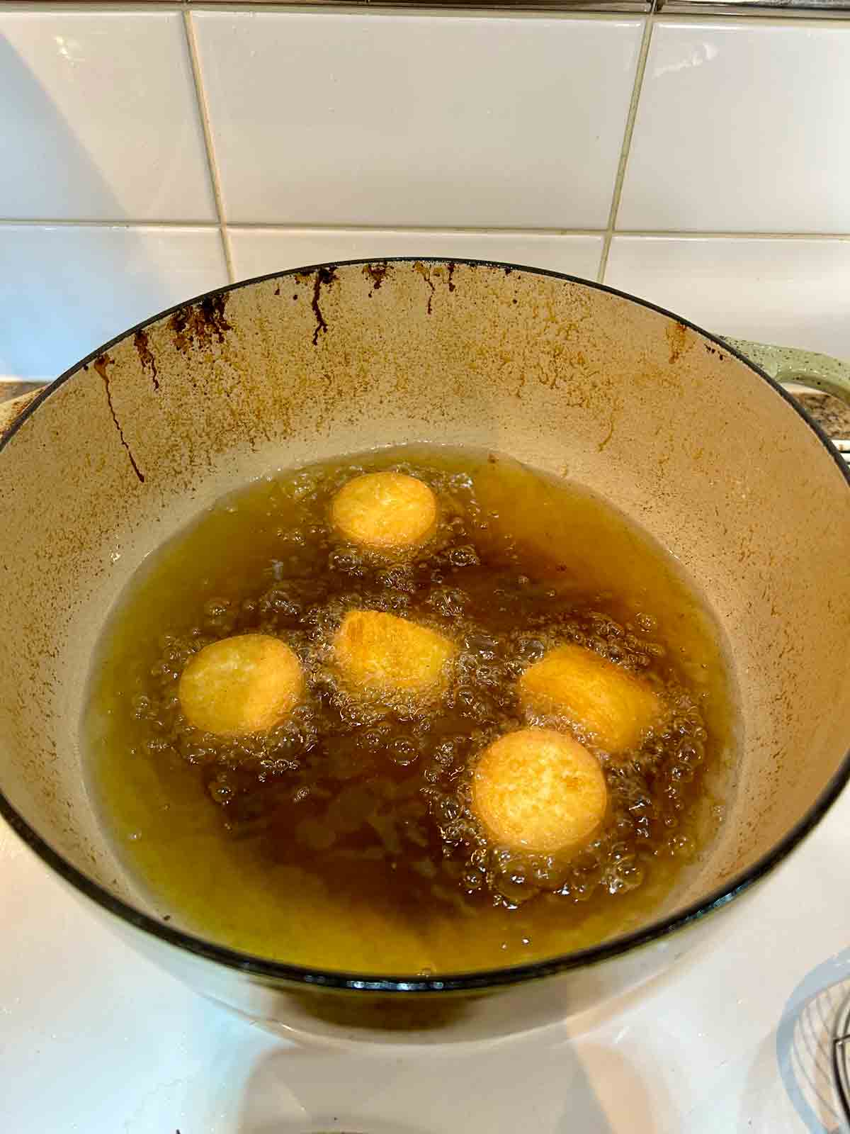 egg tofu slices being deep fried in Dutch oven.