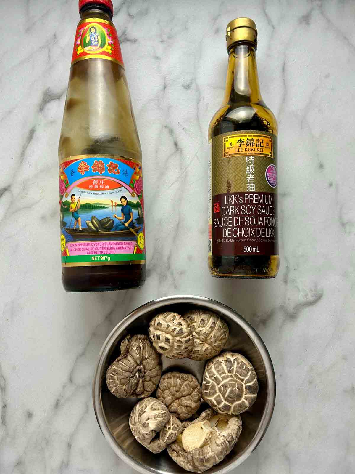 bottle of oyster sauce, bottle of dark soy sauce, and plate of dried shiitake mushrooms.