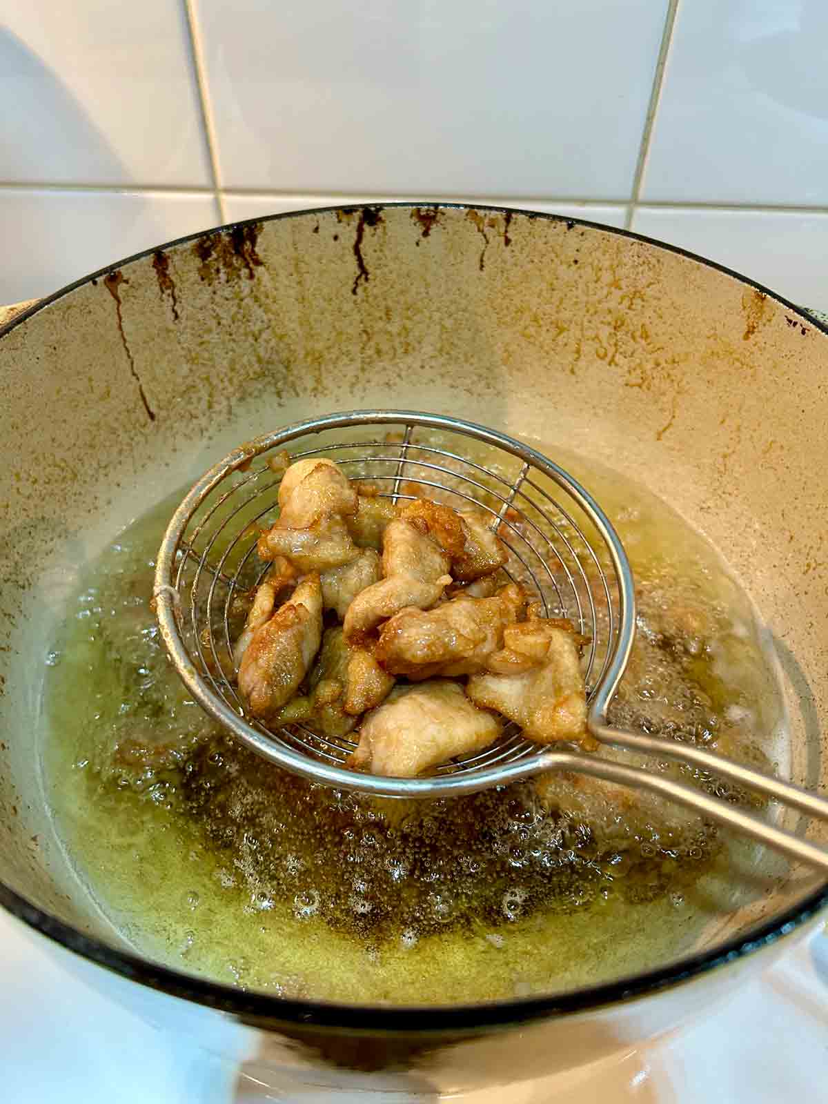 metal spider lifting out velveted meat from hot oil.