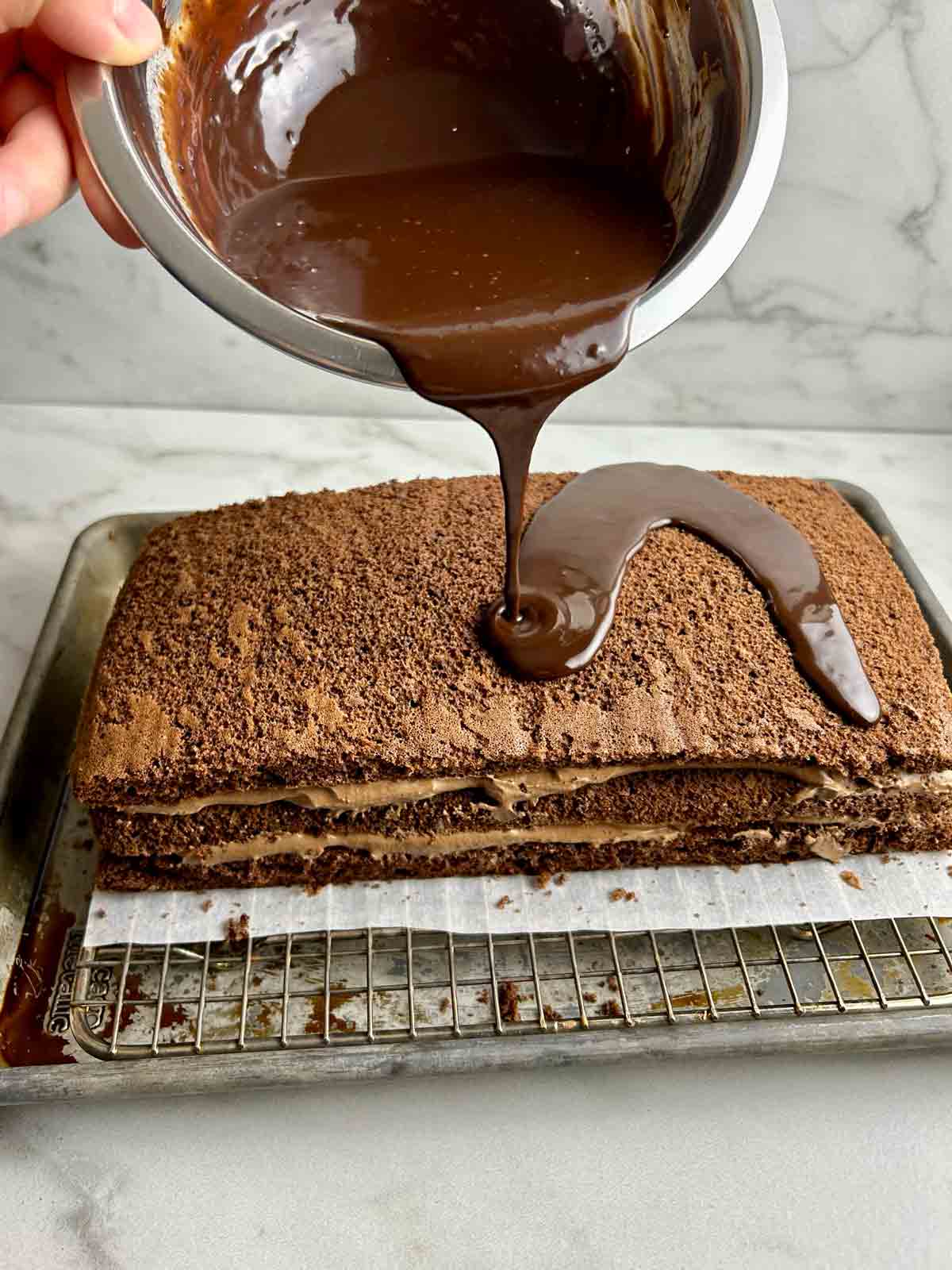 ganache being poured over top of cake.