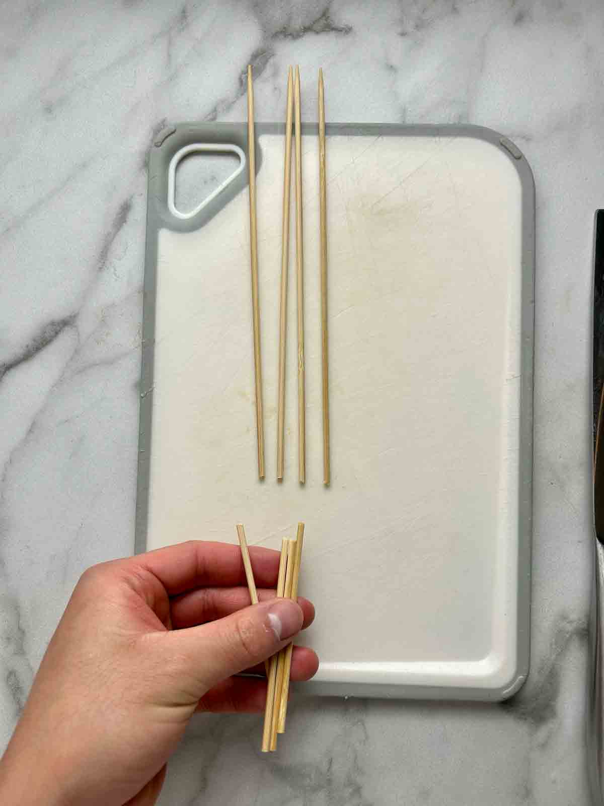 bamboo skewers being cut so they fit in frying pan.