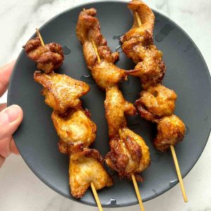 Chinese chicken on a stick on a plate.