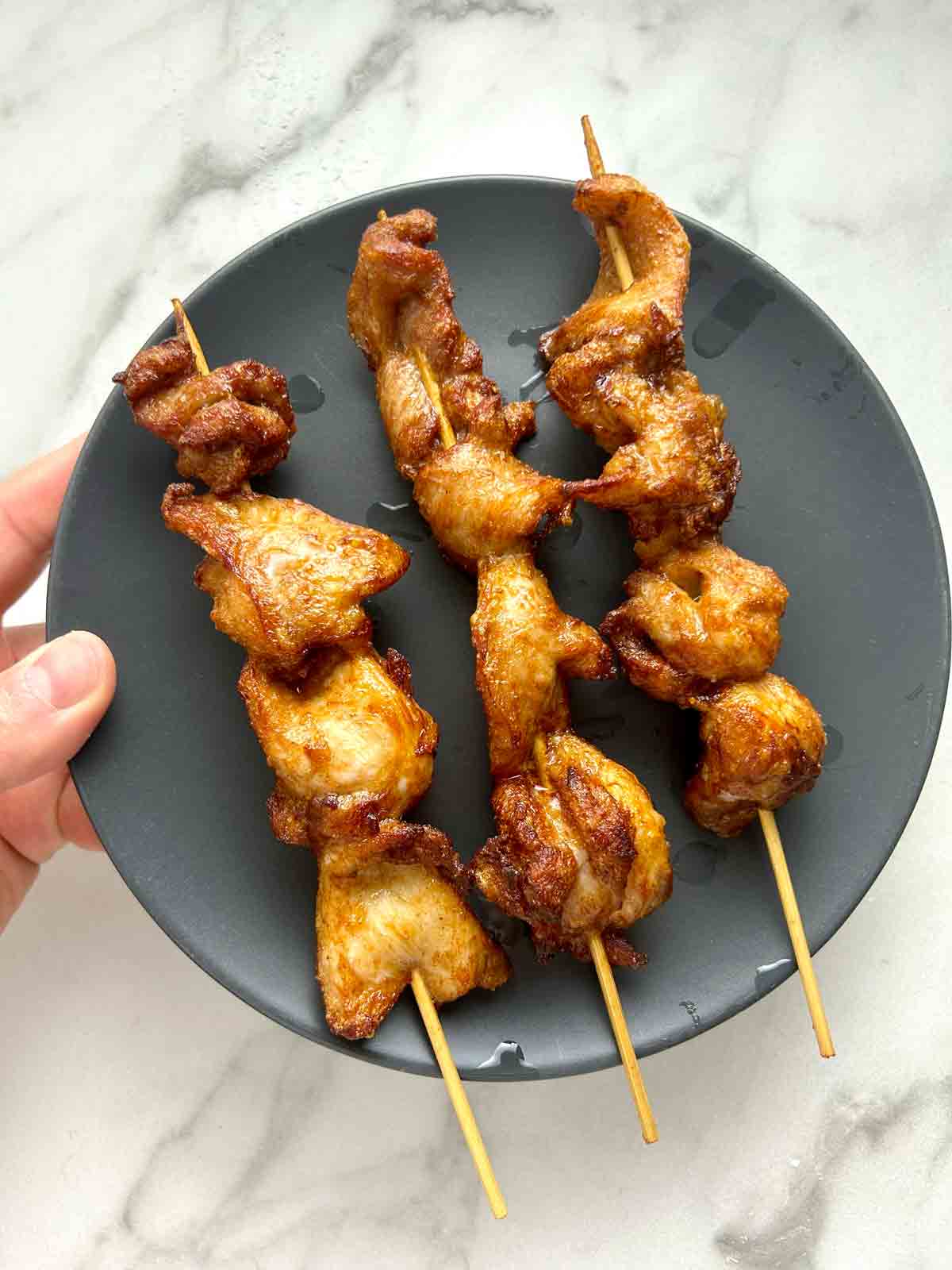 Chinese chicken on a stick on a plate.