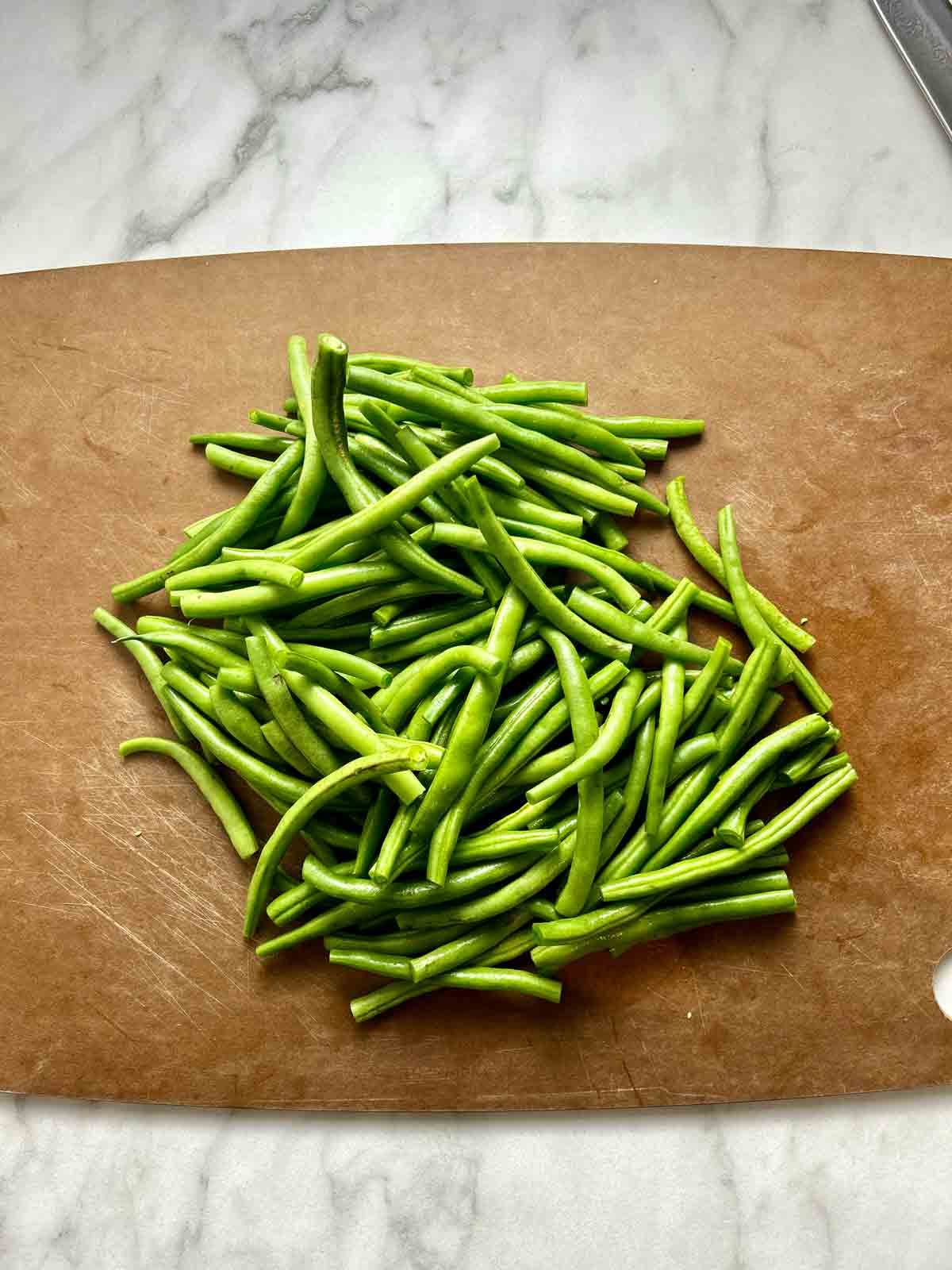 green beans with ends trimmed on a cutting board