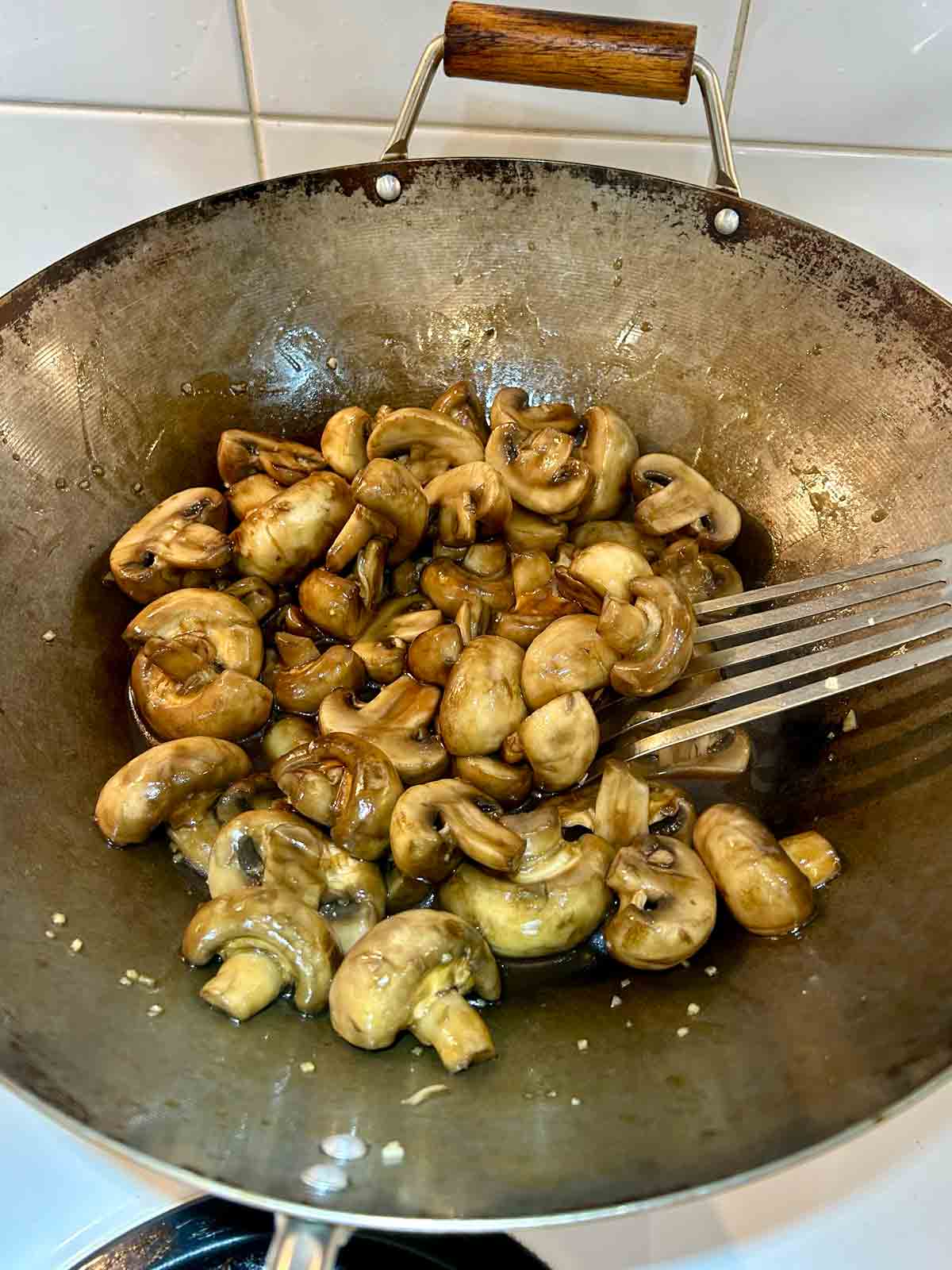 sauce being mixed with mushrooms.