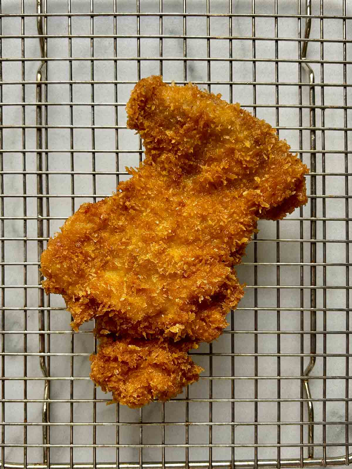 fried breaded chicken drying on wire rack.