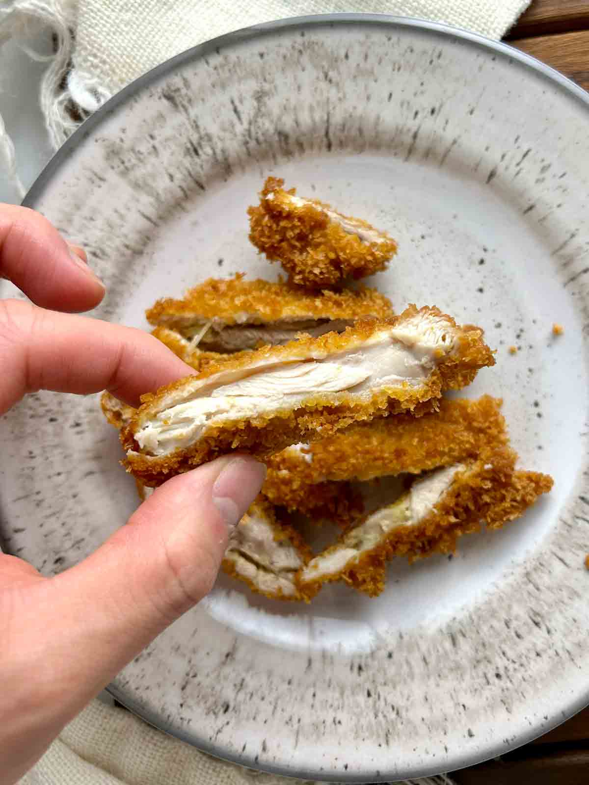 hand showing slice of breaded chicken.