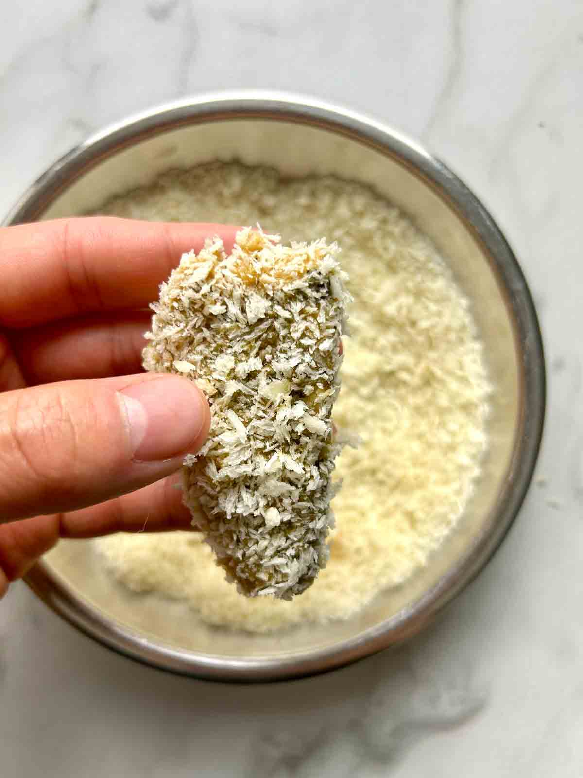 hand holding breaded sardine.