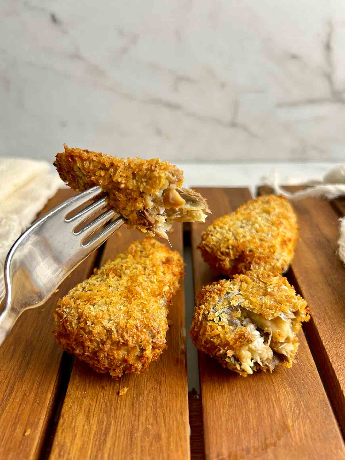 fork holding piece of air-fried sardine.