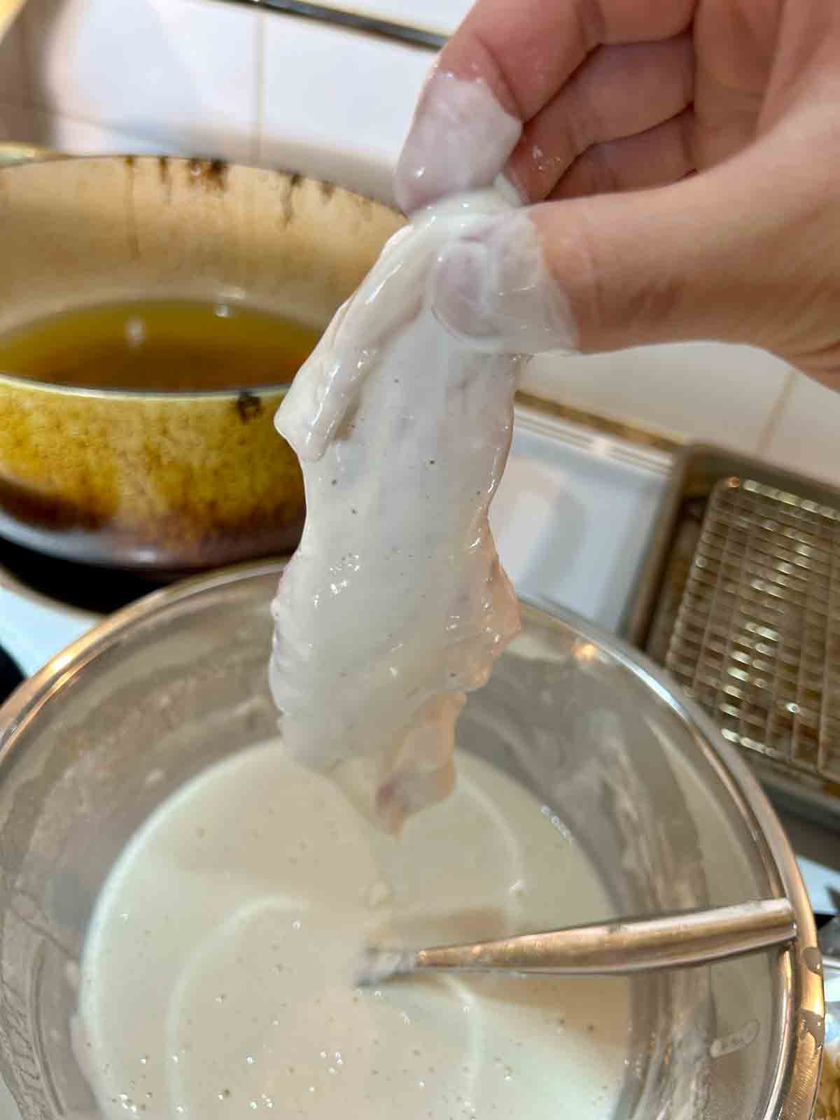 chicken being coated in wet batter.