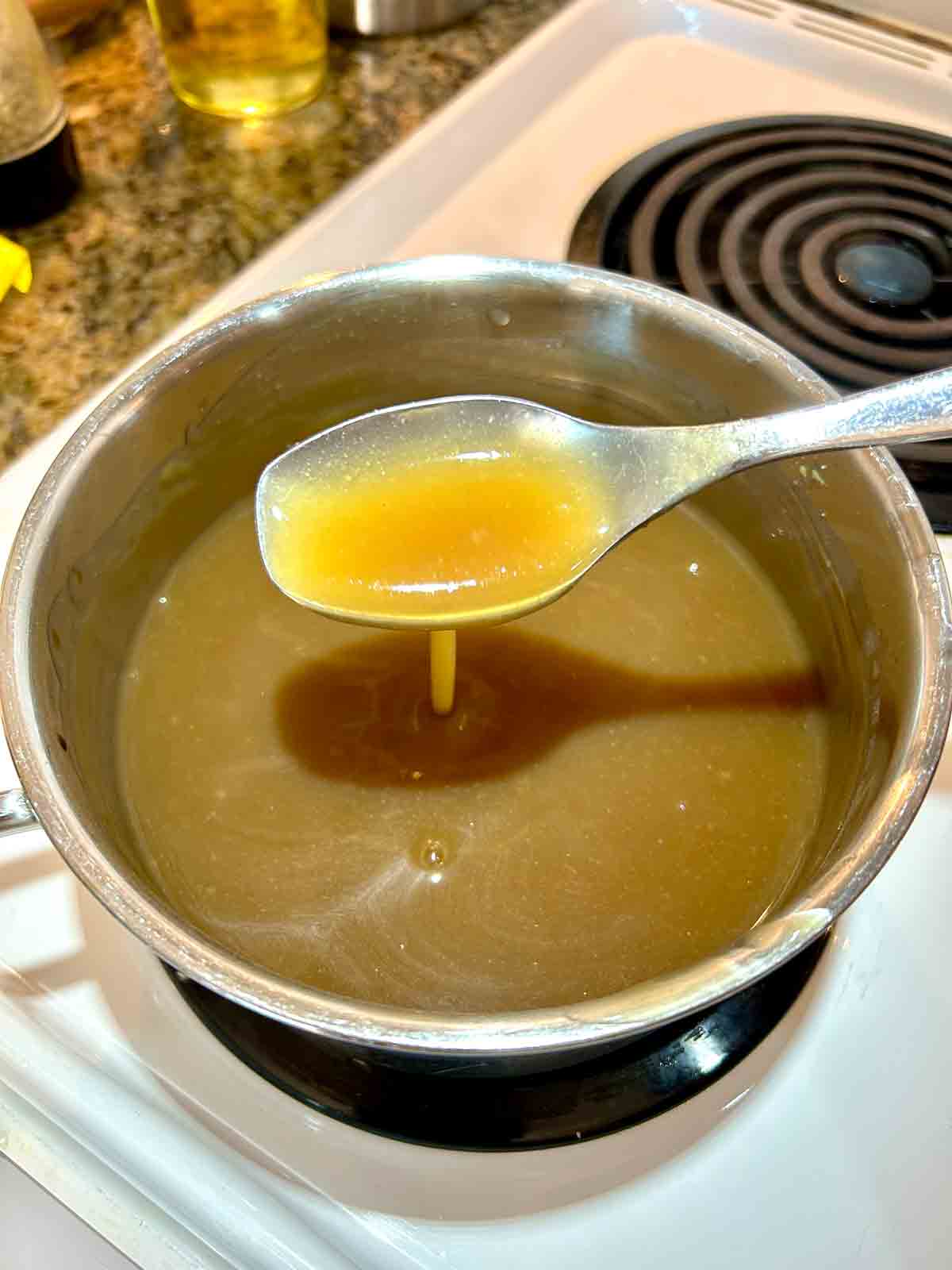 spoon lifting out sauce from saucepan.