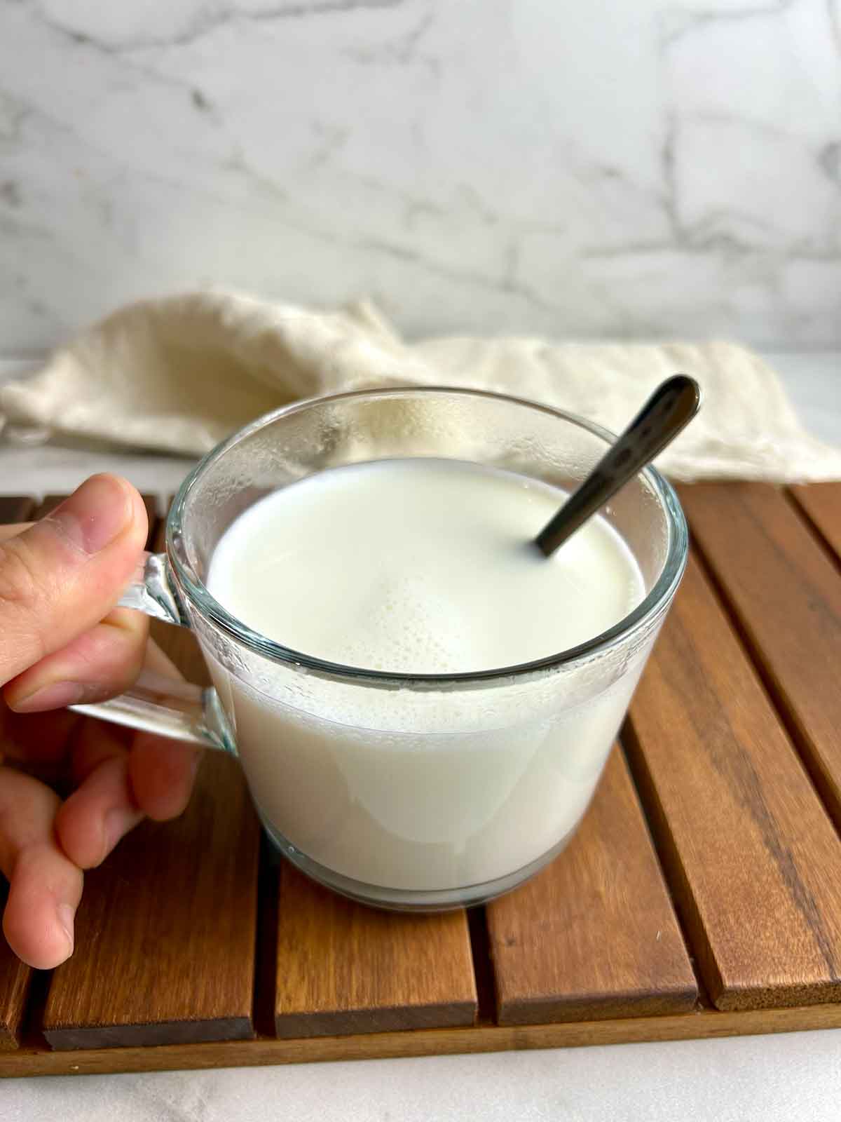 hand holding cup of almond milk.