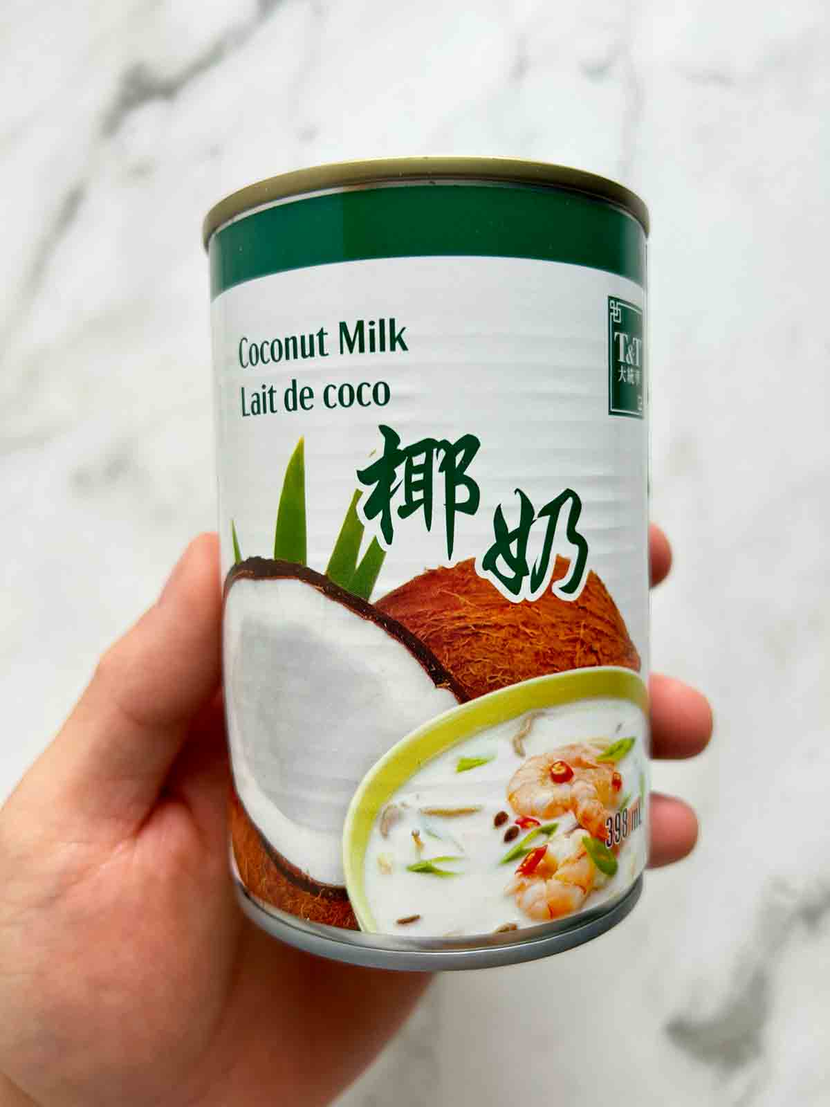 hand holding can of coconut milk.