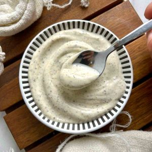 spoon lifting black pepper mayo from bowl of sauce.