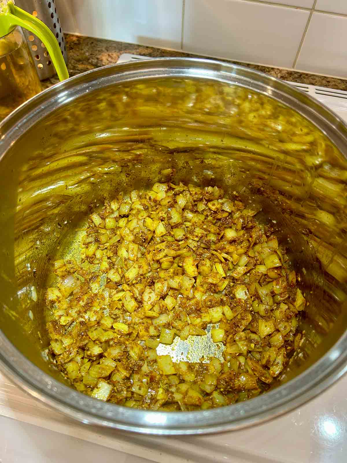 spices being cooked with onions and garlic in pot.