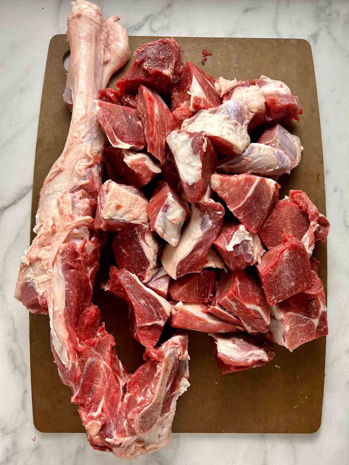 lamb bone and sliced off meat chunks on cutting board.