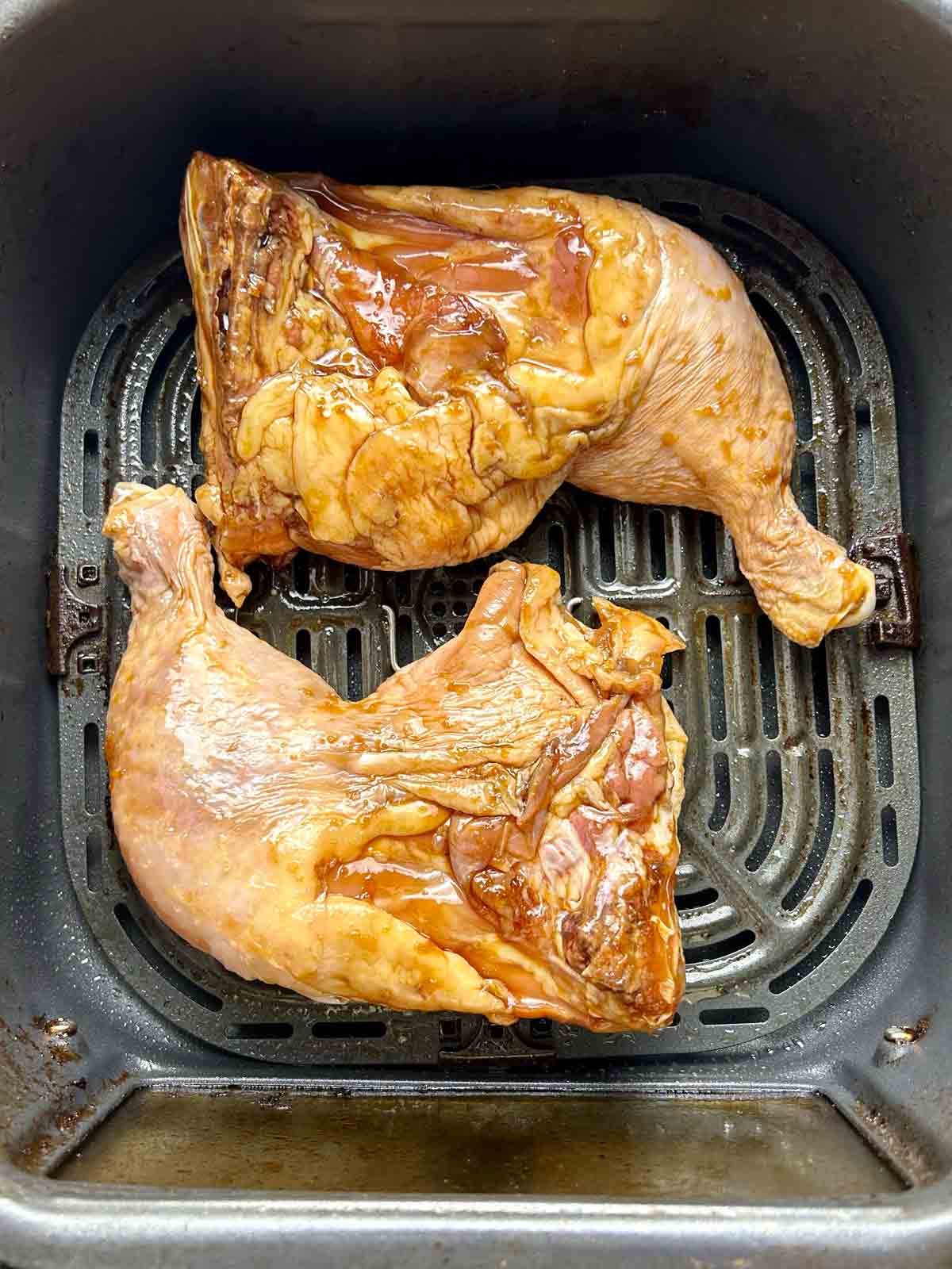 raw chicken legs in air fryer basket.