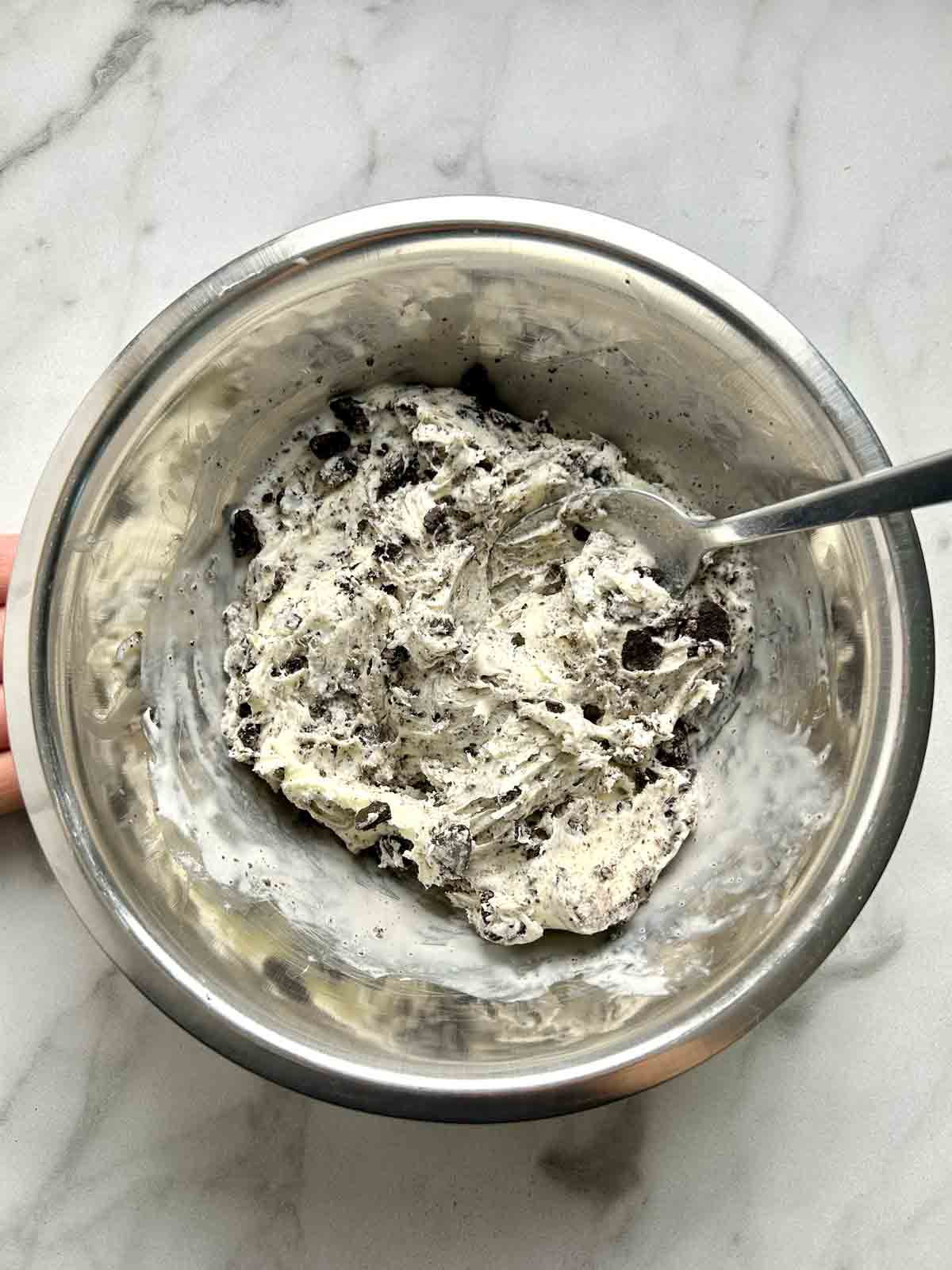 ice cream mixed with Oreos in bowl.