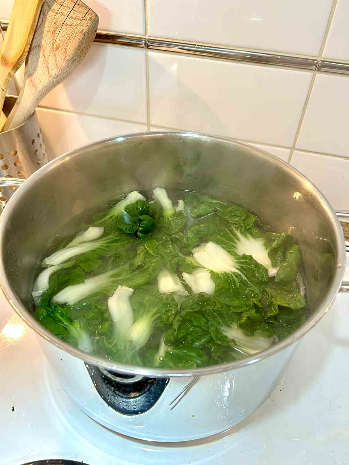 bok choy being blanched in pot of water.