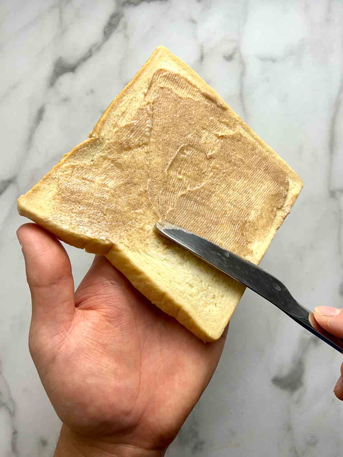 spreading sugar butter mixture onto slice of bread.