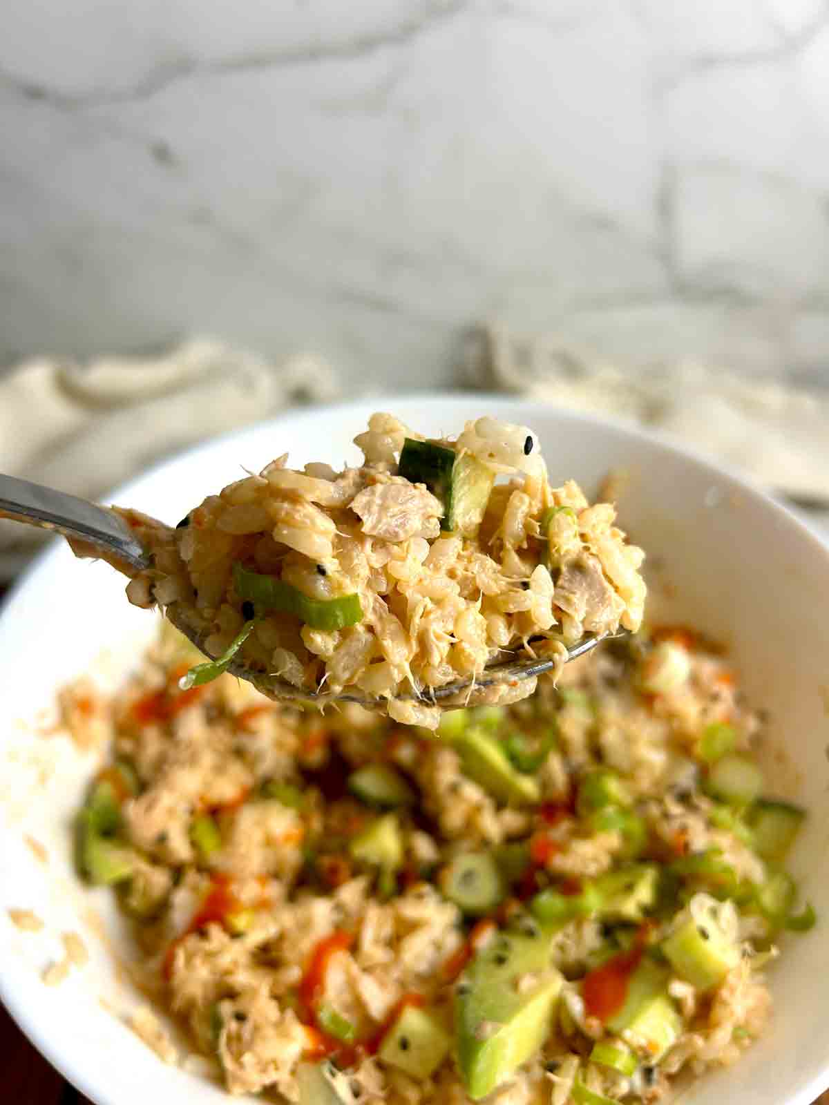 spoon lifting tuna rice from bowl.