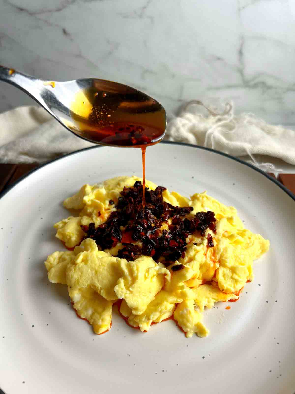 chili oil being spooned onto scrambled eggs.