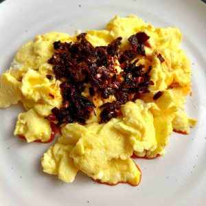 close up of chili oil crisps on top of scrambled eggs.