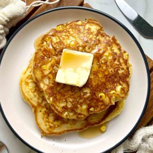 corn pancakes with slab of butter and maple syrup.