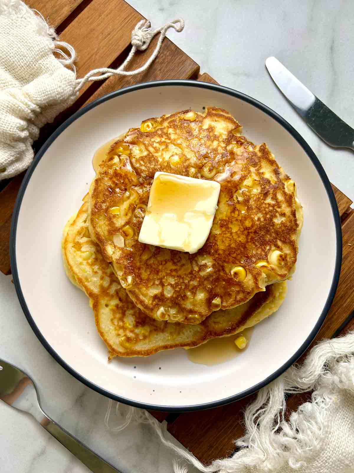 corn pancakes with slab of butter and maple syrup.