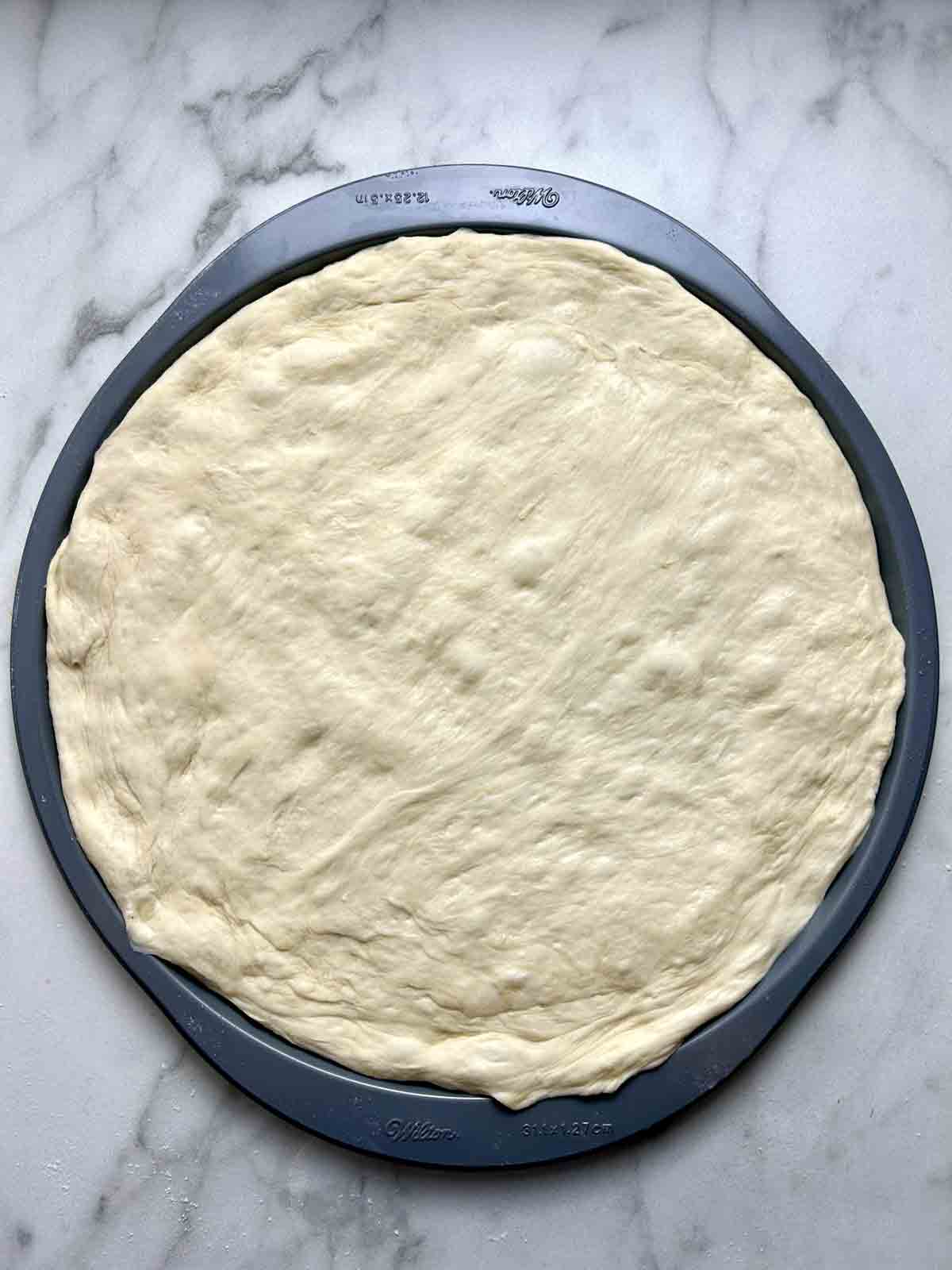 dough stretched into pizza pan.