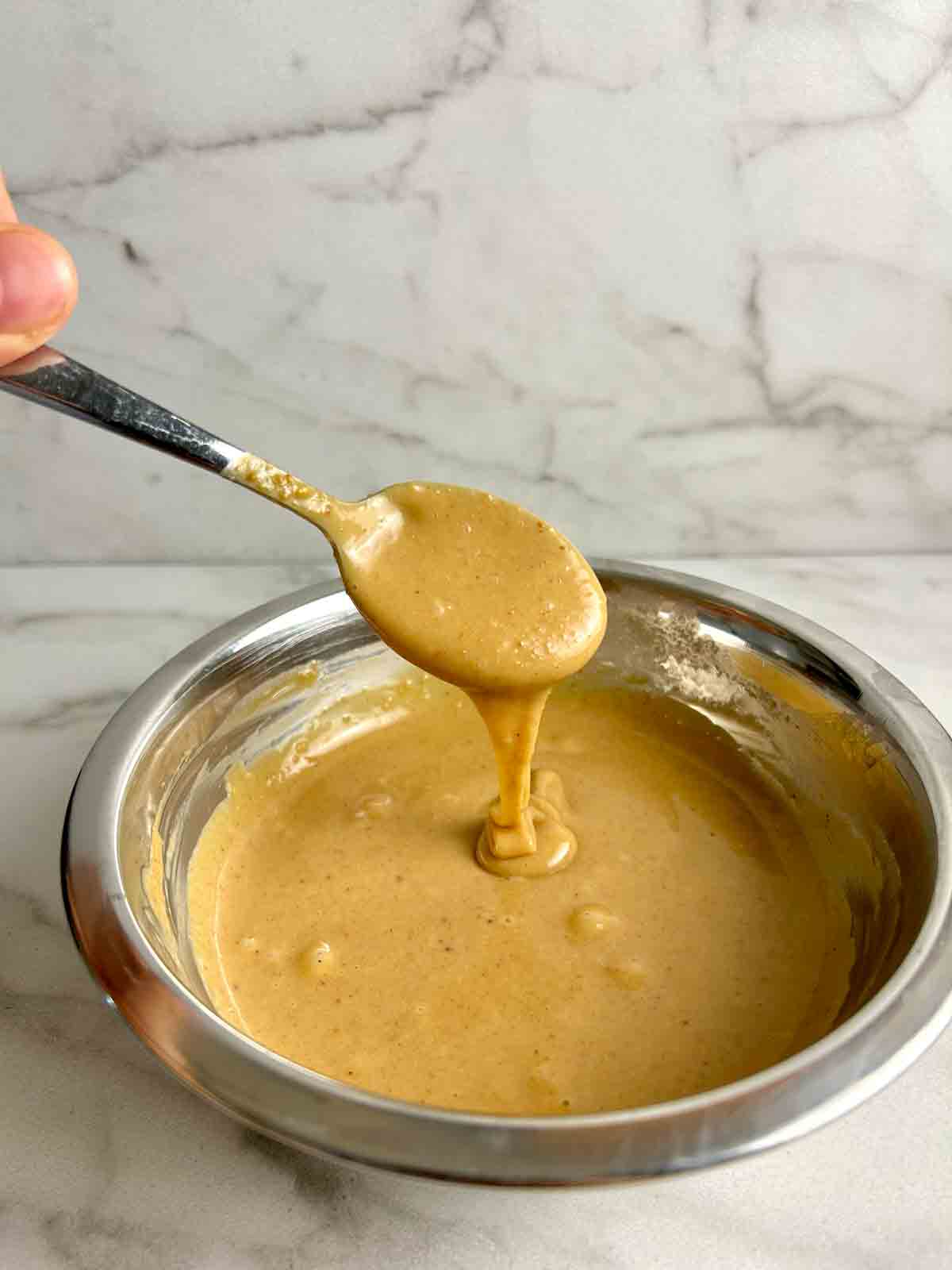 spoon lifting peanut butter sauce out of bowl.