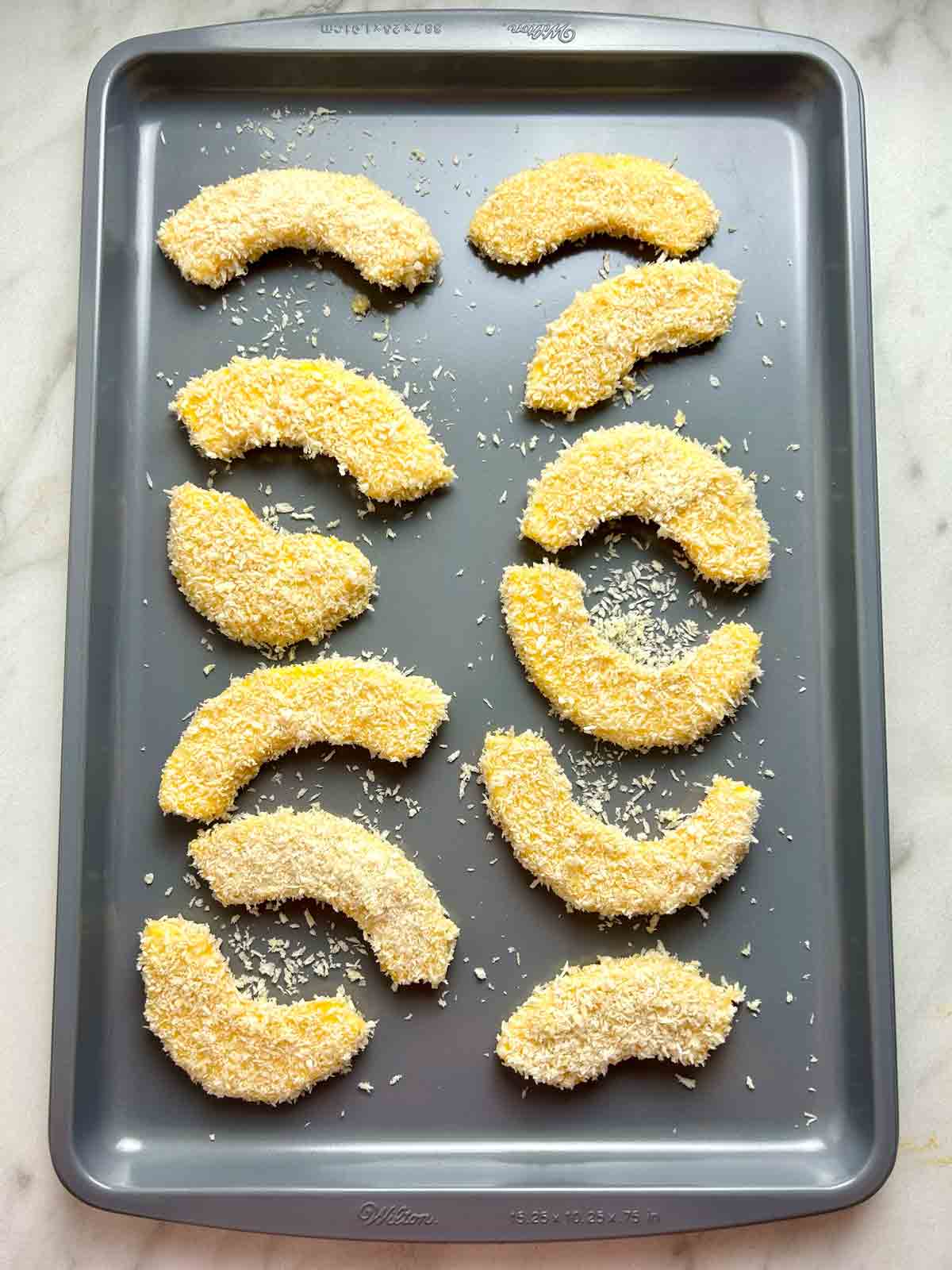 breaded pumpkin slices on baking sheet.