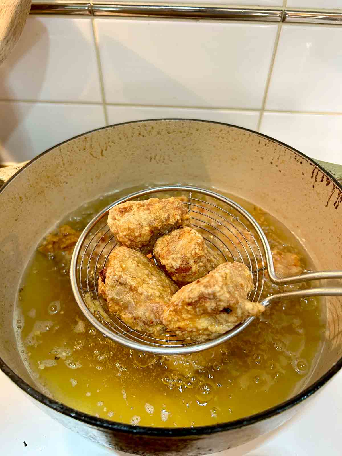 deep fried spare ribs being lifted out of oil in metal spider.