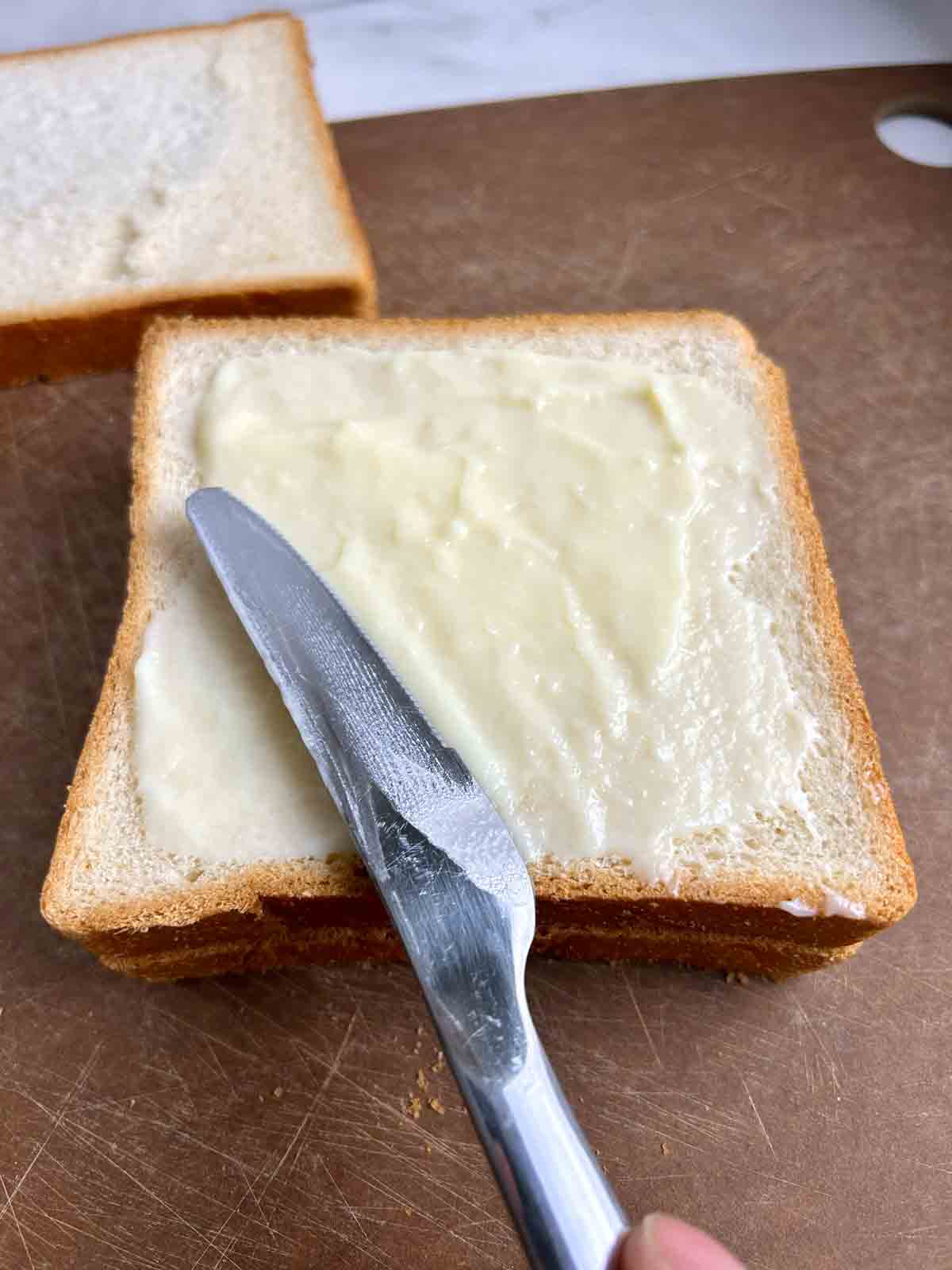 spreading custard filling on slice of bread.