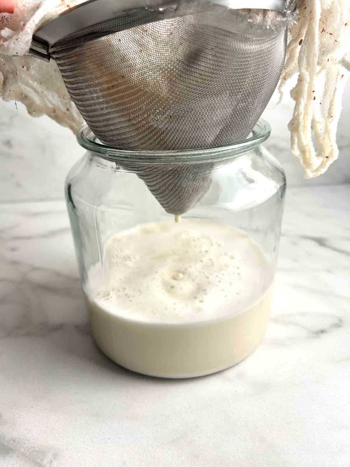 rice milk being strained through sieve