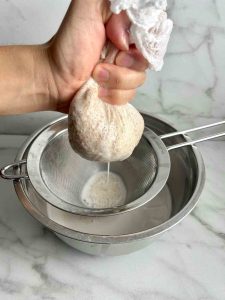 squeezing rice milk through cheesecloth.