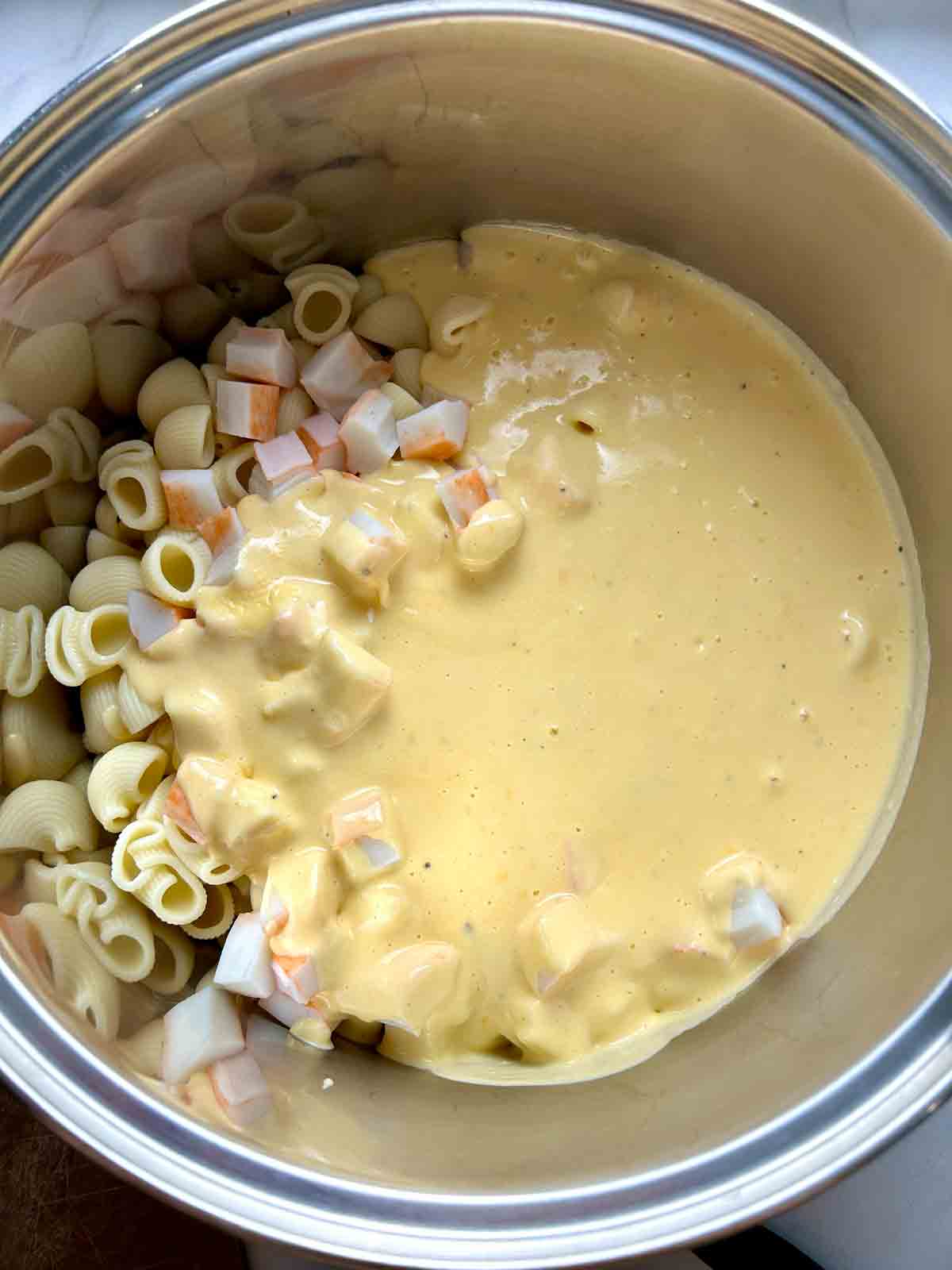 cheese sauce and crab on top of macaroni in pot.