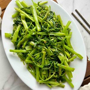 ong choy stir-fry on white plate.