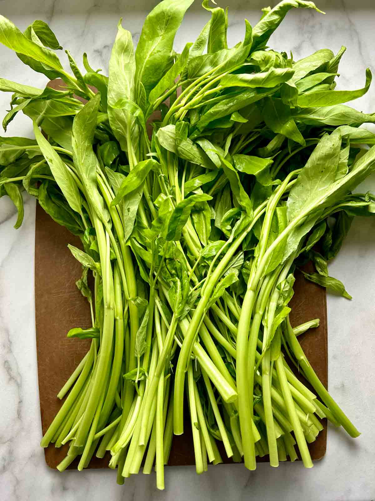 bundle of ong choy on cutting board.