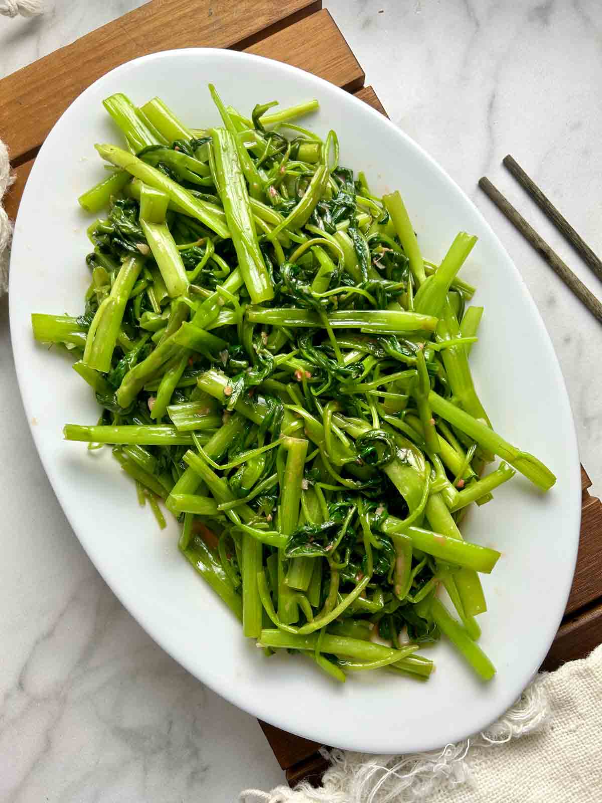 ong choy stir-fry on white plate.