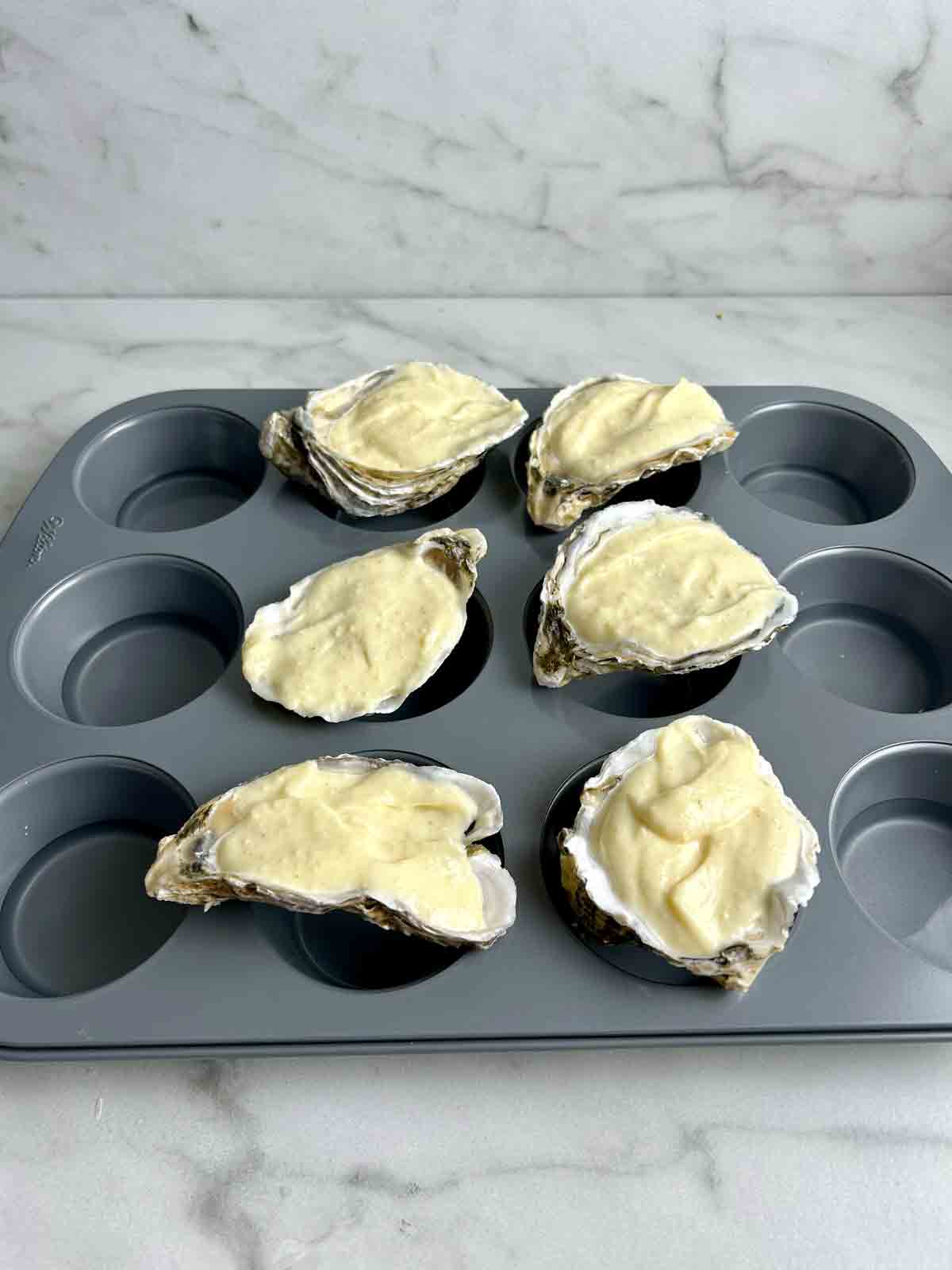 oysters being balanced on cupcake pan.