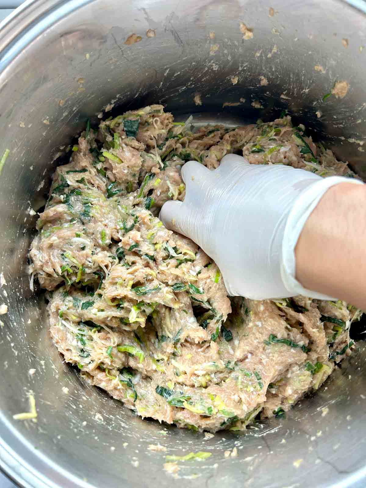 mixing pork and leek filling with hands.