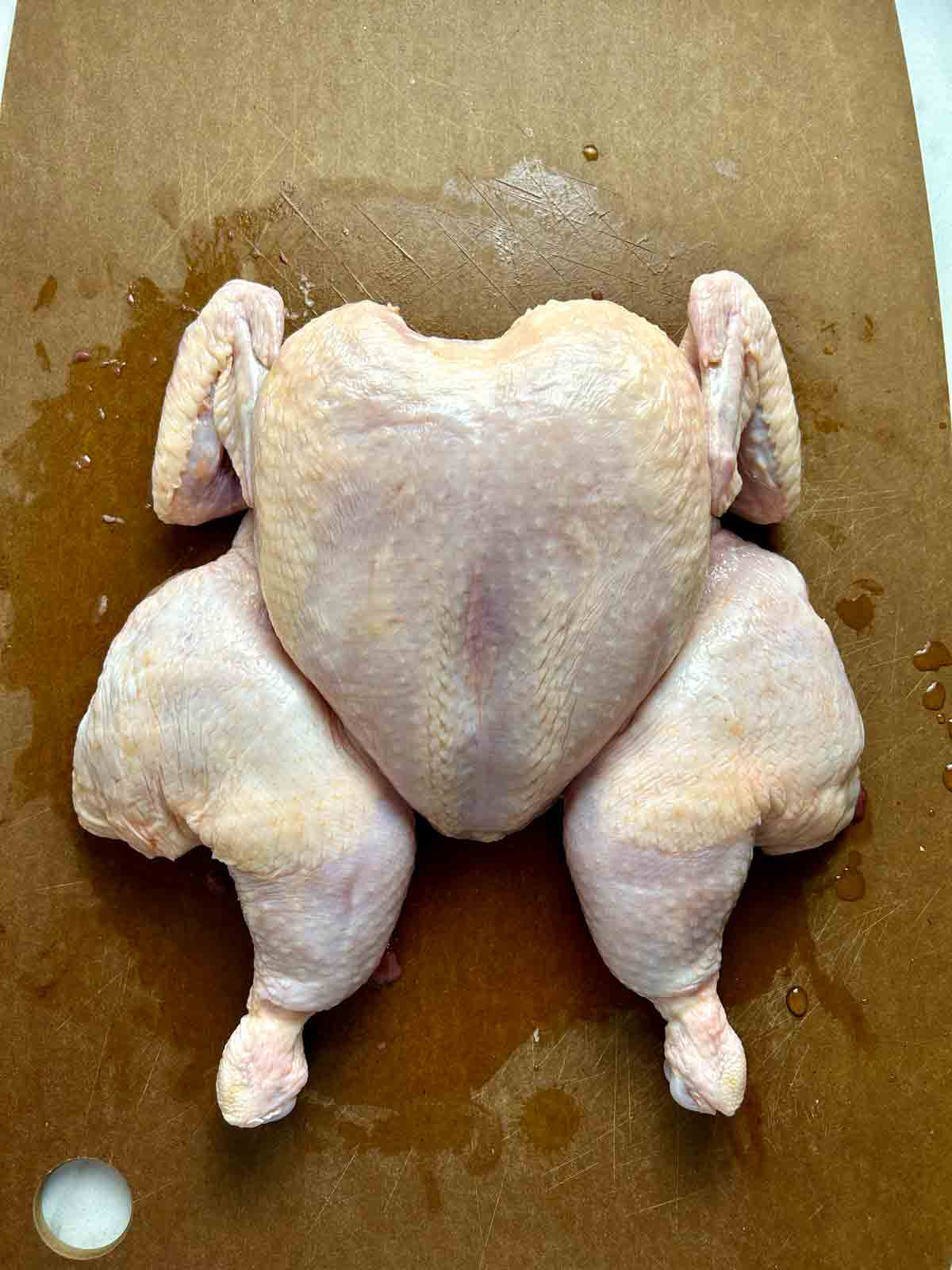 spatchcocked chicken on cutting board.