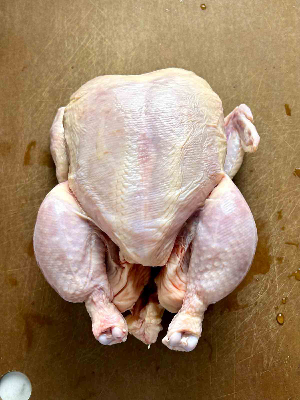 whole raw chicken on cutting board.