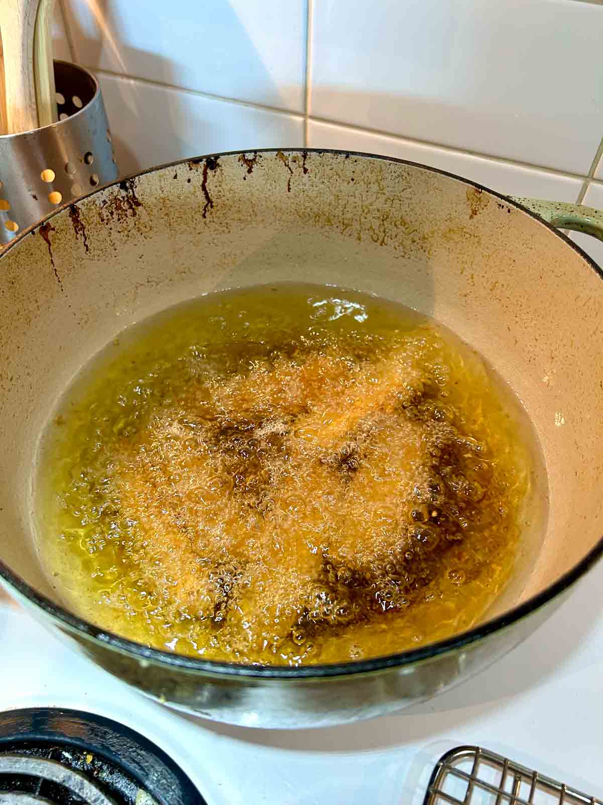 breaded Spam sticks being deep-fried in oil.