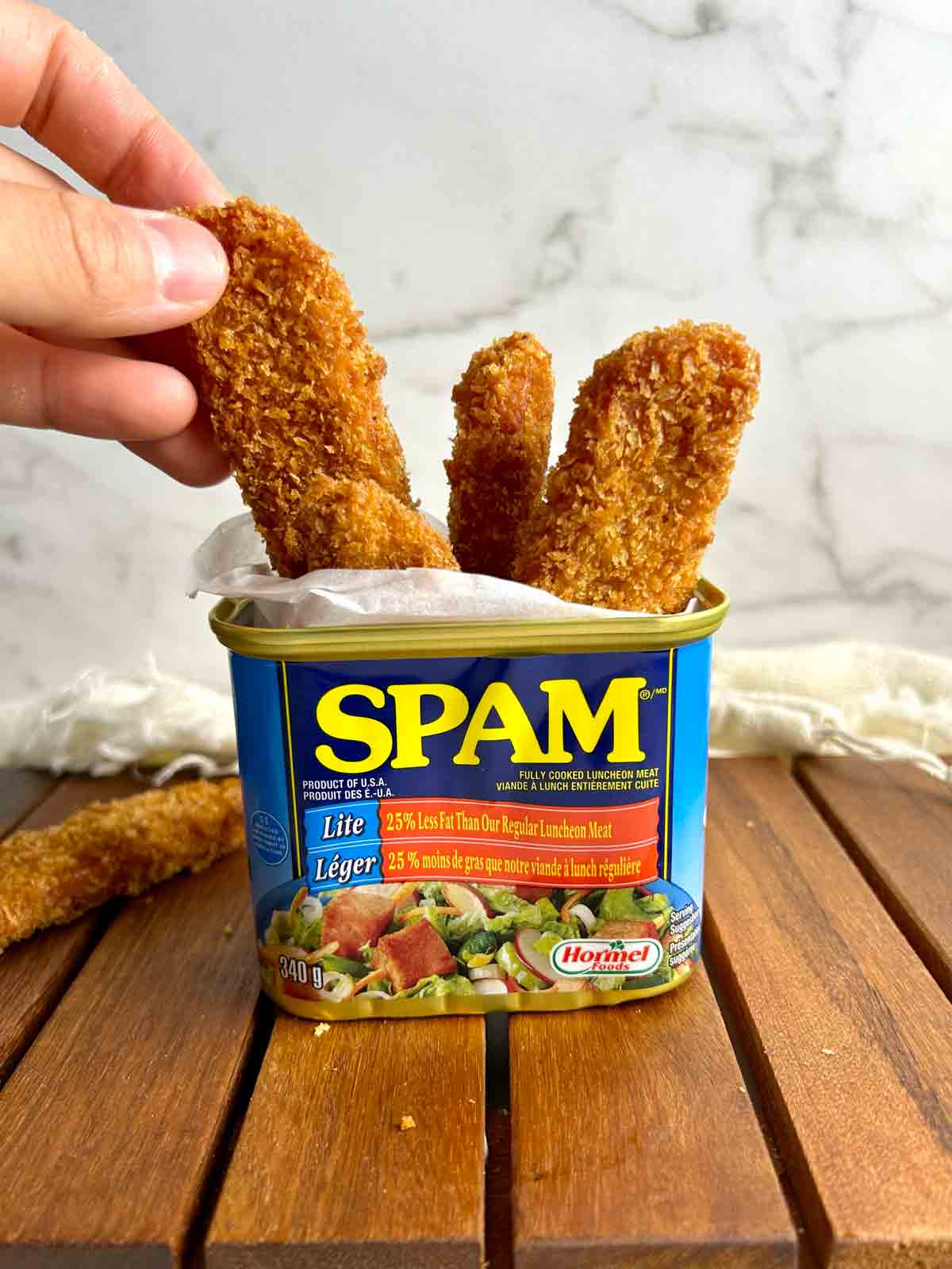 hand pulling out Spam fry from can.