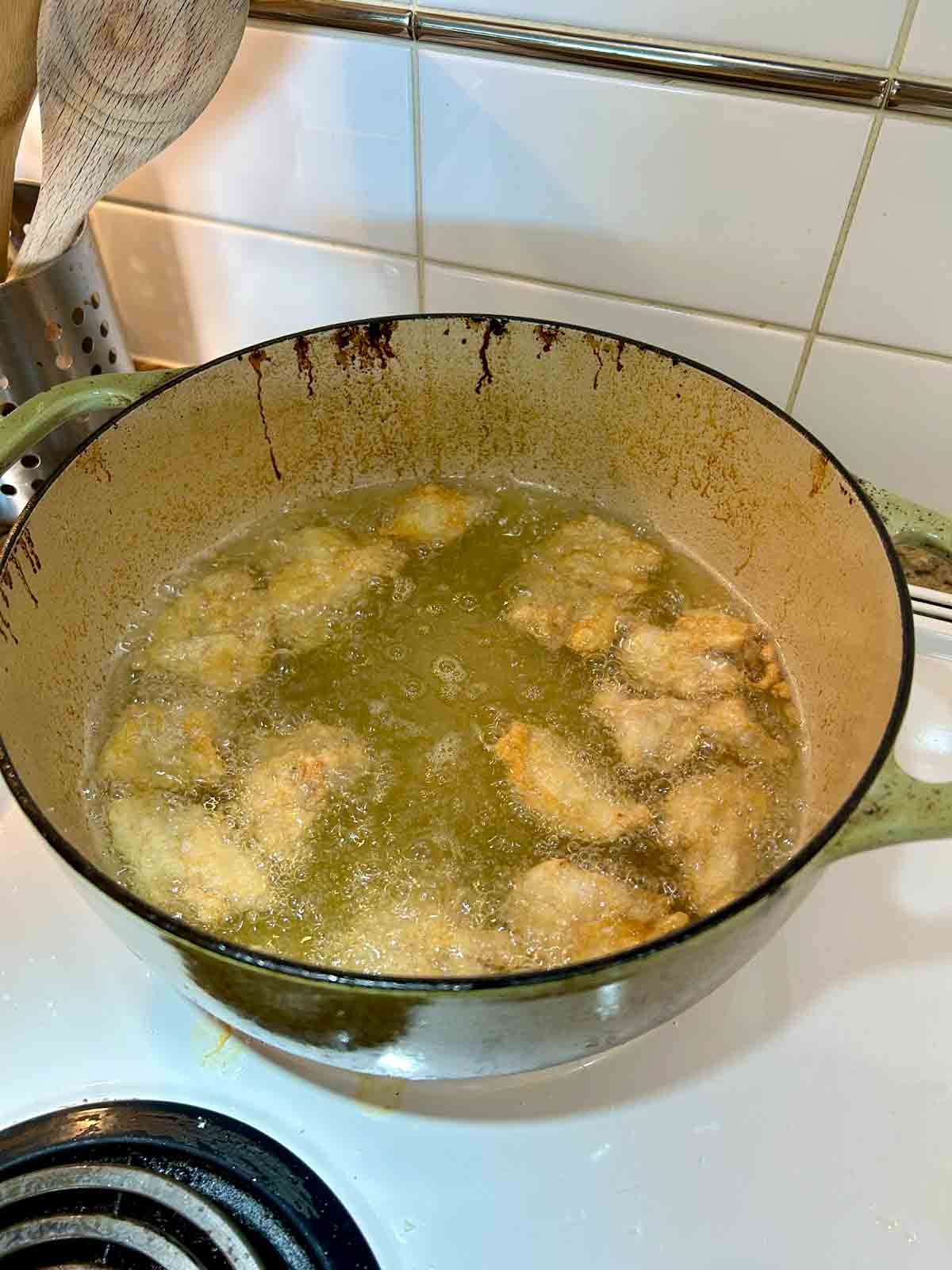 chicken pieces being deep-fried in hot oil.