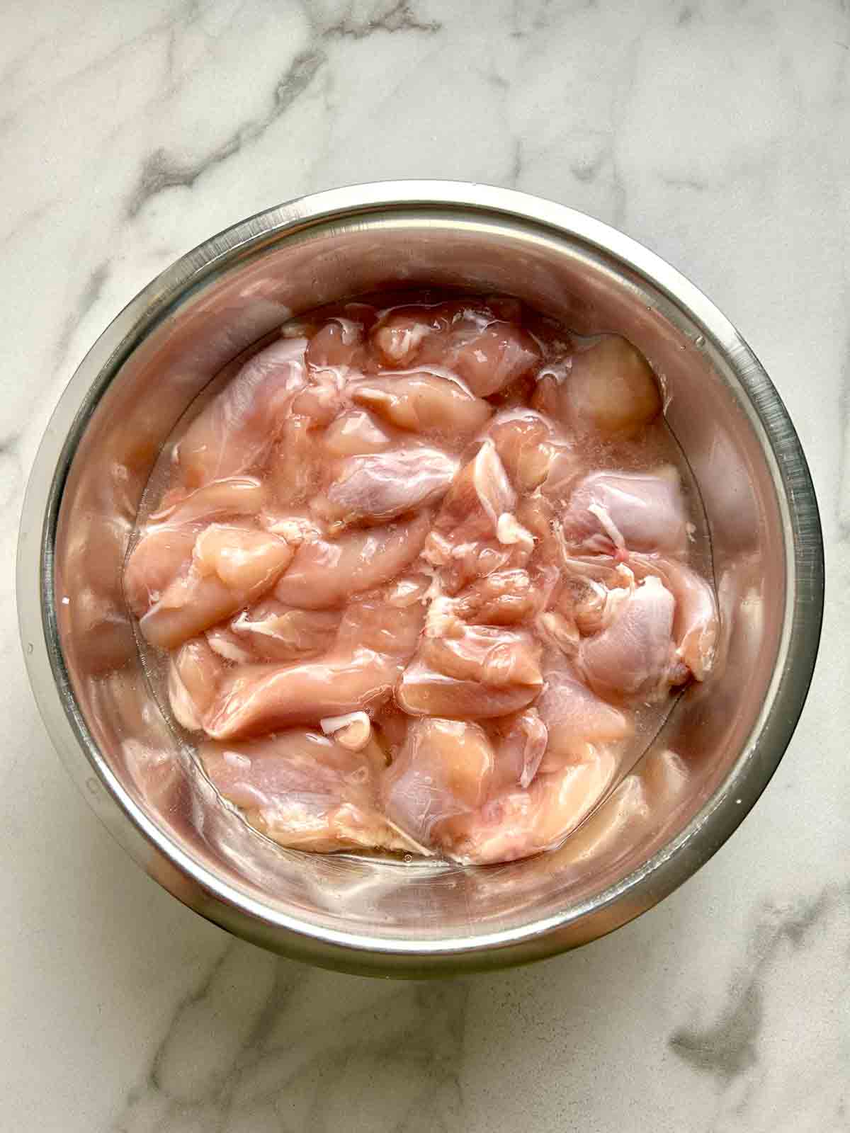 bowl of chicken meat being marinated.