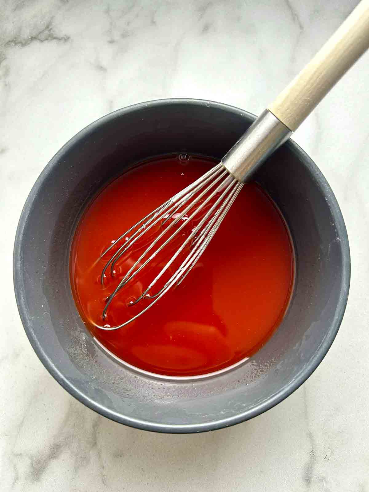 sweet and sour sauce being whisked in bowl.