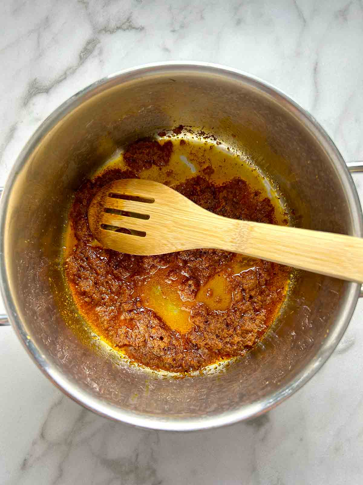 tom yum paste being sizzled in oil in pot.